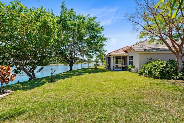 view of yard featuring a sunroom, a water view, and fence