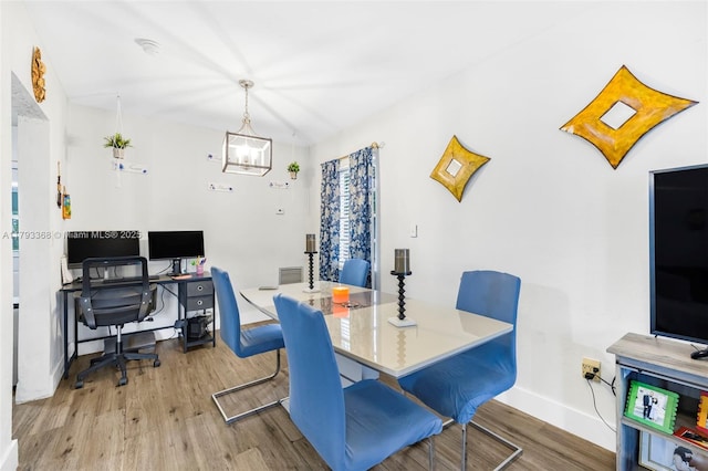 dining space with an inviting chandelier, baseboards, wood finished floors, and visible vents