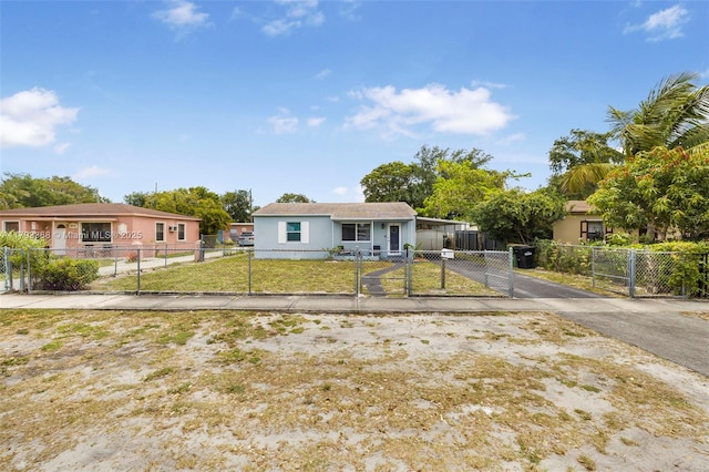 bungalow-style house with a front yard, stucco siding, a gate, a fenced front yard, and driveway