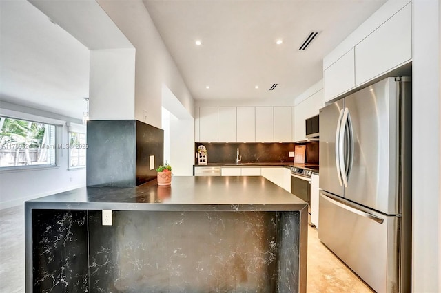 255 Ridgewood Rd, Key Biscayne, FL 33149 - kitchen with appliances with stainless steel finishes, modern cabinets, white cabinets, decorative backsplash, and dark countertops