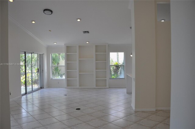 spare room featuring crown molding, baseboards, light tile patterned flooring, and visible vents