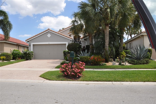 mediterranean / spanish-style home with an attached garage, stucco siding, driveway, and a tiled roof
