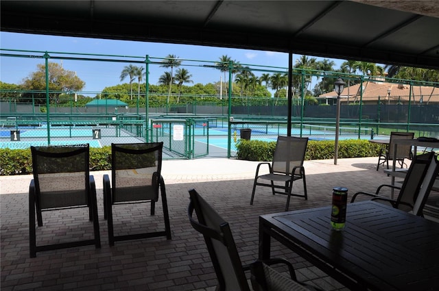 view of patio / terrace featuring a tennis court and fence