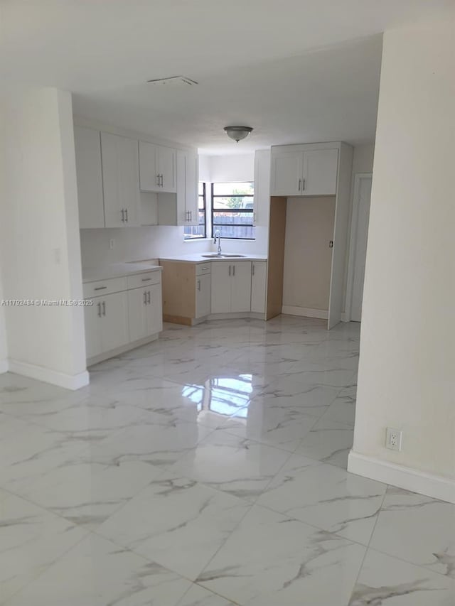 kitchen with a sink, baseboards, and marble finish floor