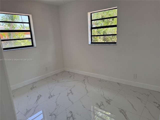 empty room featuring baseboards and marble finish floor