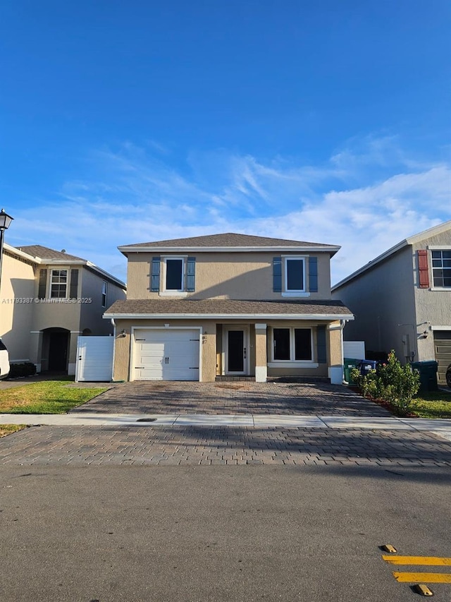 traditional home with a shingled roof, stucco siding, an attached garage, and driveway