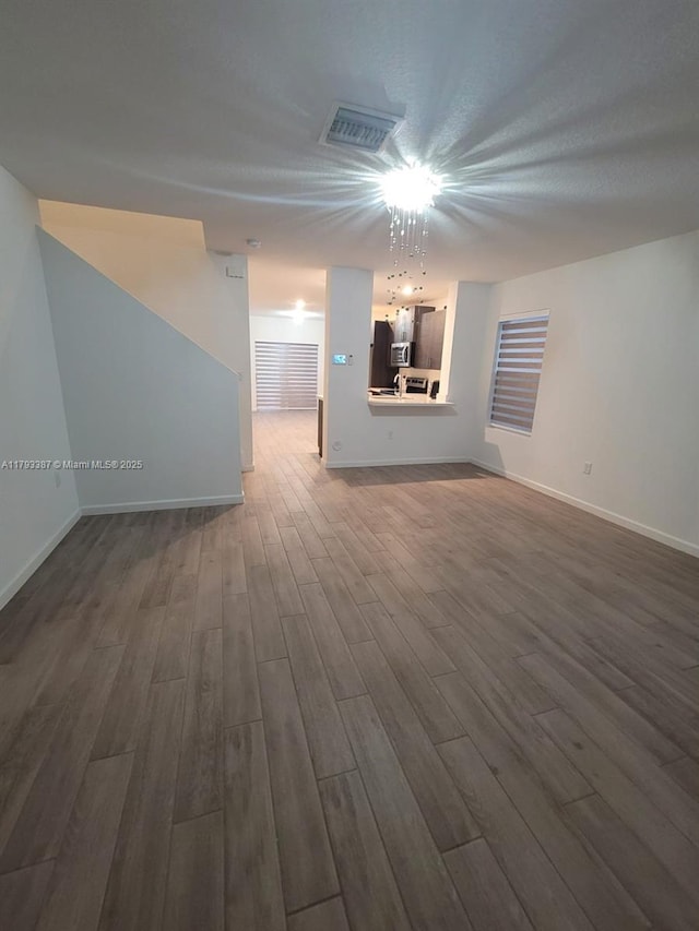 unfurnished living room with baseboards, dark wood finished floors, and visible vents