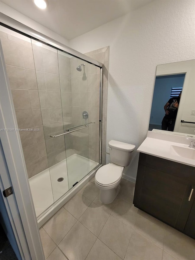 bathroom featuring vanity, toilet, tile patterned floors, baseboards, and a stall shower