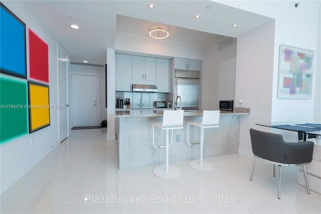 950 Brickell Bay Dr Unit 4710, Miami, FL 33131 - kitchen featuring appliances with stainless steel finishes, wall chimney range hood, recessed lighting, a peninsula, and tasteful backsplash