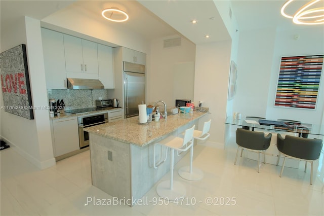 950 Brickell Bay Dr Unit 4710, Miami, FL 33131 - kitchen with backsplash, visible vents, range hood, baseboards, and stainless steel appliances