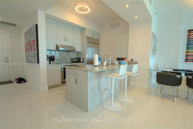 950 Brickell Bay Dr Unit 4710, Miami, FL 33131 - kitchen featuring light stone countertops, built in fridge, baseboards, decorative backsplash, and visible vents