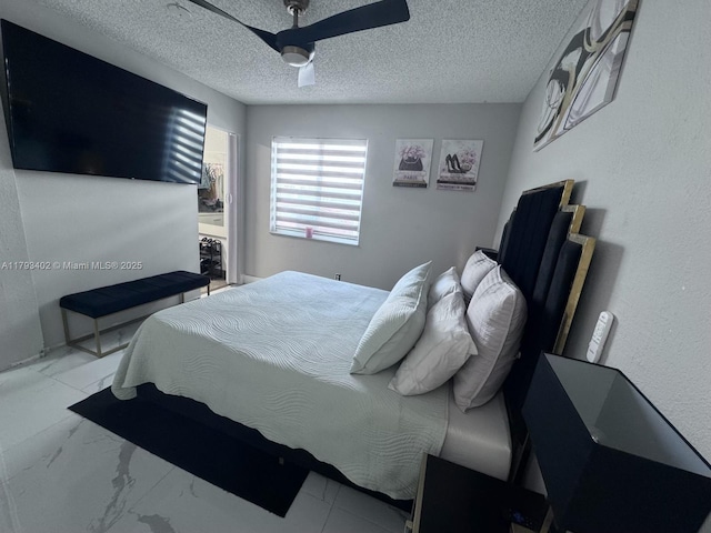 bedroom with ceiling fan, a textured ceiling, and marble finish floor