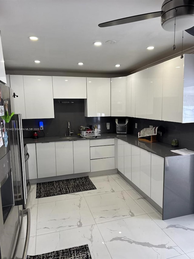 kitchen featuring marble finish floor, dark countertops, modern cabinets, recessed lighting, and white cabinetry