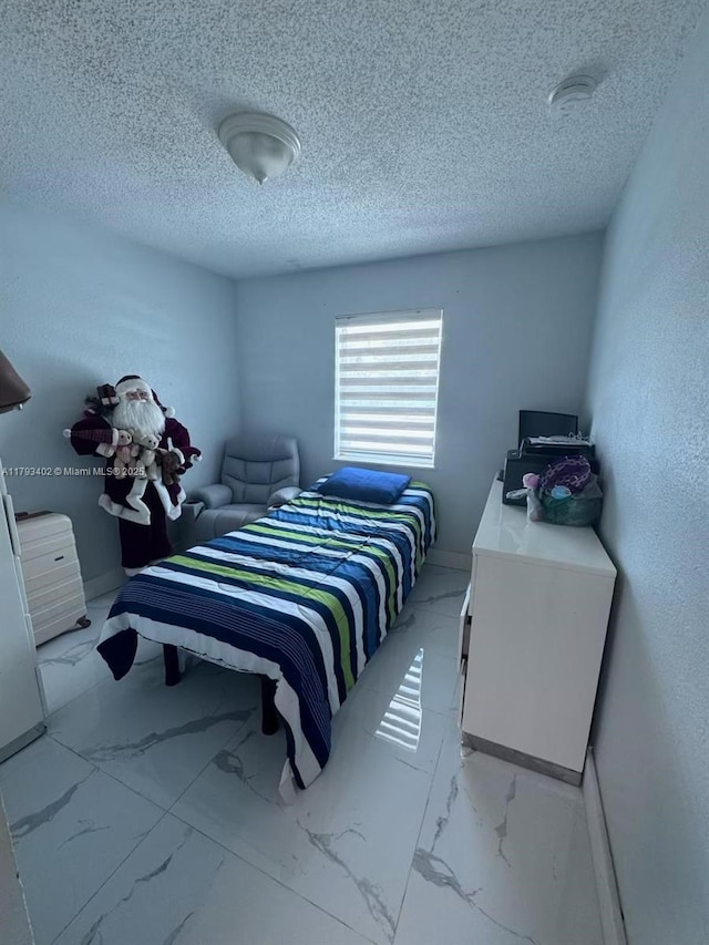 bedroom featuring a textured ceiling and marble finish floor