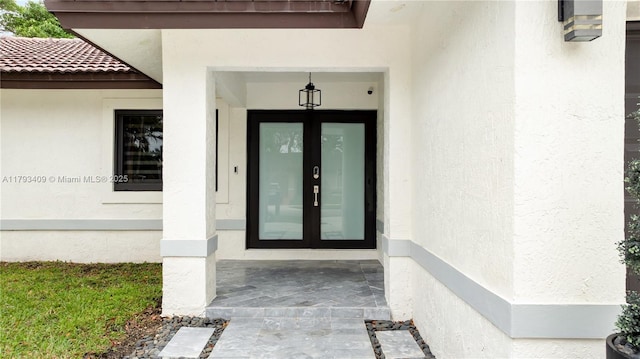 view of exterior entry with stucco siding and french doors
