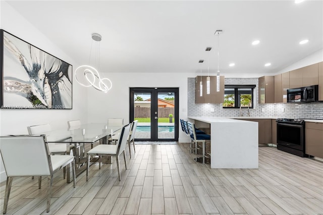 kitchen featuring modern cabinets, a kitchen bar, light countertops, tasteful backsplash, and range with electric cooktop