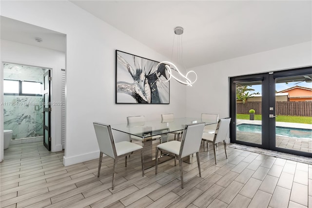 dining room featuring vaulted ceiling, baseboards, wood tiled floor, and french doors