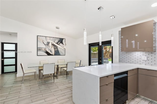 kitchen with a peninsula, modern cabinets, light countertops, backsplash, and gray cabinetry