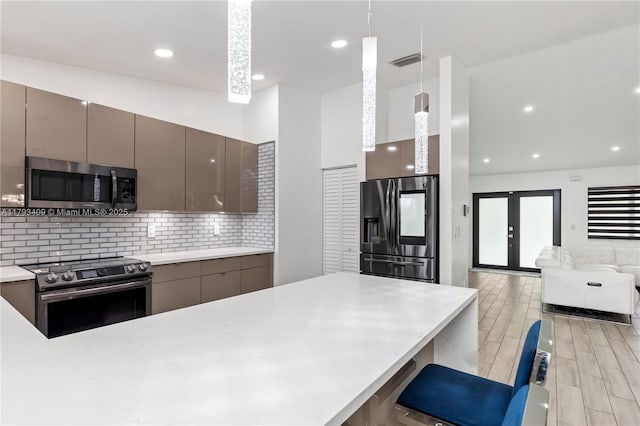 kitchen with modern cabinets, stainless steel appliances, tasteful backsplash, and visible vents