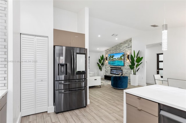 kitchen featuring light wood-style floors, light countertops, vaulted ceiling, and stainless steel fridge with ice dispenser