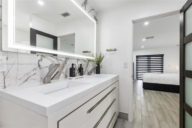 bathroom featuring vanity, recessed lighting, visible vents, and tasteful backsplash