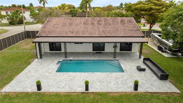 view of swimming pool featuring a lawn, fence, a fenced in pool, and a patio area
