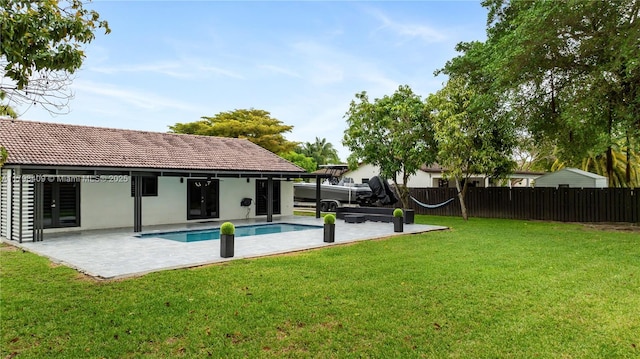 rear view of house featuring french doors, fence, a fenced in pool, a yard, and a patio