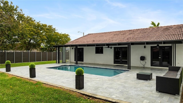 back of property with fence, stucco siding, an outdoor pool, french doors, and a patio