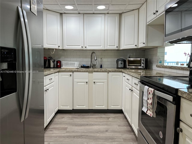 2655 Collins Ave Unit 1405, Miami Beach, FL 33140 - kitchen with a toaster, white cabinetry, a paneled ceiling, light wood finished floors, and appliances with stainless steel finishes