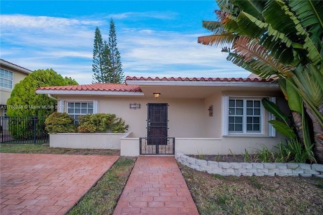 view of front facade with a fenced front yard, a tile roof, and stucco siding