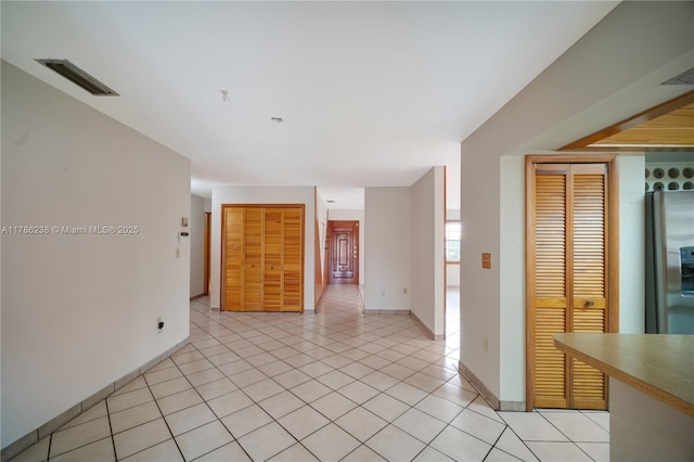 interior space featuring baseboards, visible vents, and light tile patterned floors