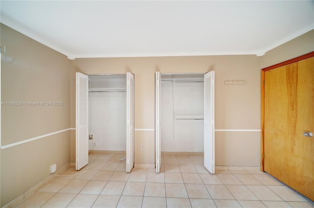 unfurnished bedroom featuring light tile patterned floors and two closets
