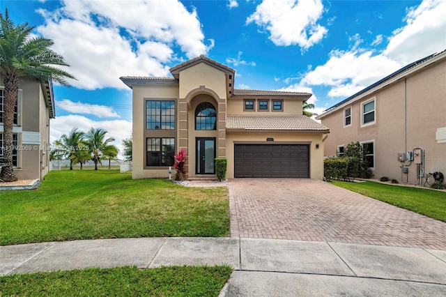 mediterranean / spanish home with a tiled roof, decorative driveway, a front lawn, and stucco siding
