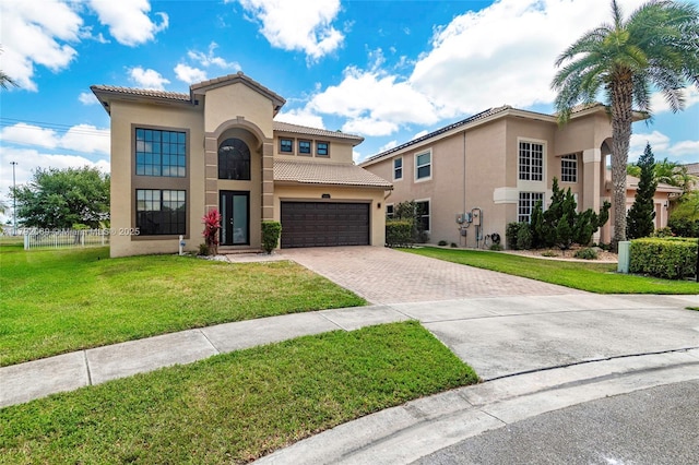 mediterranean / spanish-style house with fence, a front lawn, stucco siding, a tiled roof, and driveway