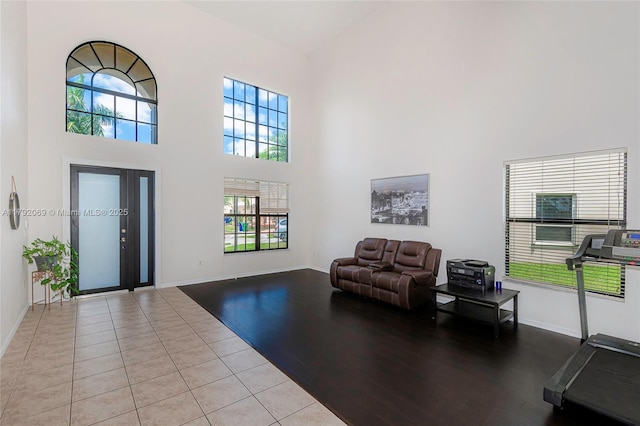 tiled foyer featuring baseboards, a wealth of natural light, and a towering ceiling