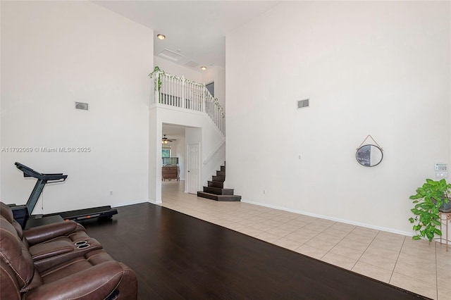 living area featuring stairs, tile patterned floors, visible vents, and a towering ceiling