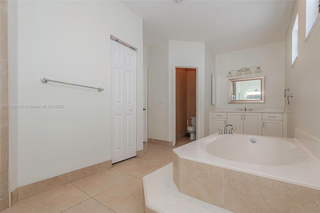 full bathroom with tile patterned flooring, vanity, toilet, a garden tub, and a closet