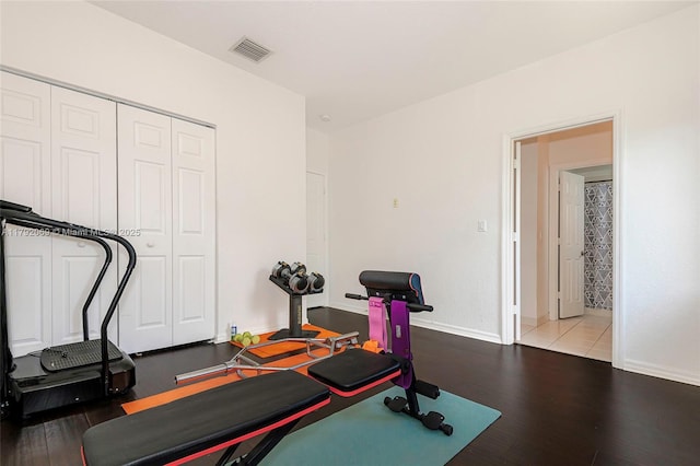 exercise area with visible vents, baseboards, and wood finished floors