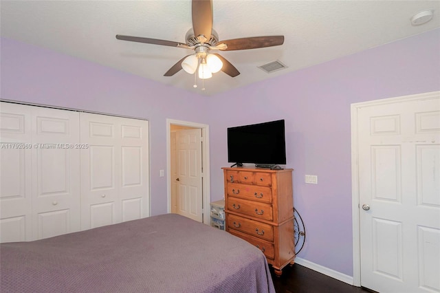 bedroom with dark wood finished floors, a ceiling fan, baseboards, visible vents, and a closet