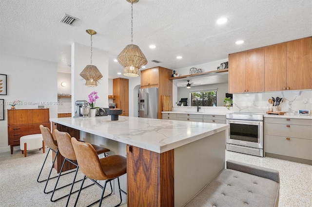kitchen with visible vents, a textured ceiling, a breakfast bar area, and stainless steel appliances