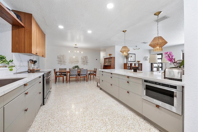 kitchen featuring stainless steel range with electric stovetop, a textured ceiling, light speckled floor, decorative light fixtures, and wall oven