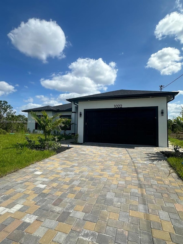 1022 Candleligth St, Lehigh Acres, FL 33974 - view of front facade with an attached garage, stucco siding, and decorative driveway