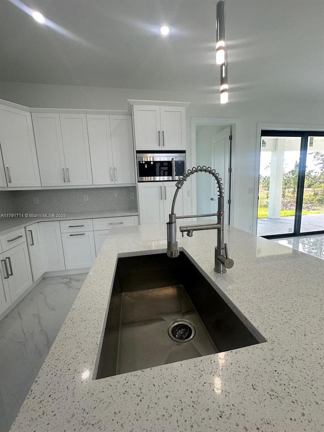 1022 Candleligth St, Lehigh Acres, FL 33974 - kitchen with a sink, stainless steel microwave, white cabinets, and light stone countertops
