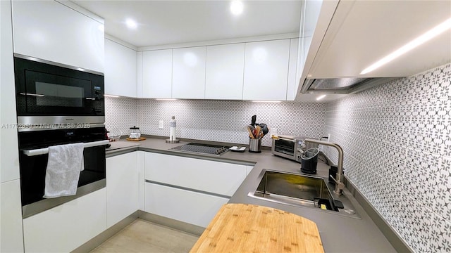 kitchen featuring white cabinetry, range hood, modern cabinets, and black appliances