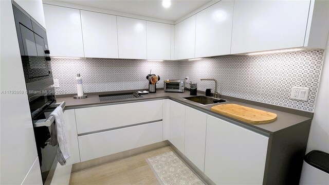 5151 Collins Ave Unit 634, Miami Beach, FL 33140 - kitchen with a toaster, a sink, white cabinetry, dark countertops, and tasteful backsplash