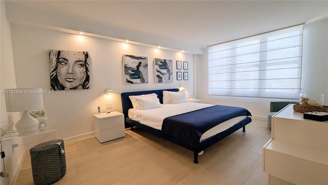 bedroom featuring baseboards and light wood finished floors