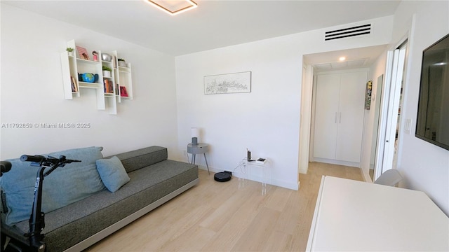 sitting room with light wood-style floors, attic access, and visible vents