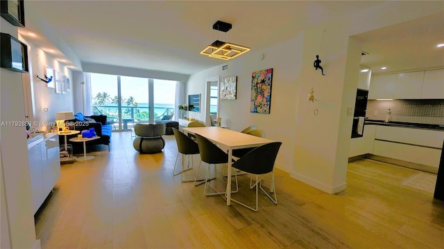 dining space with baseboards, floor to ceiling windows, recessed lighting, and light wood-style flooring