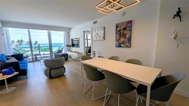 dining area with a water view, visible vents, a chandelier, and light wood finished floors