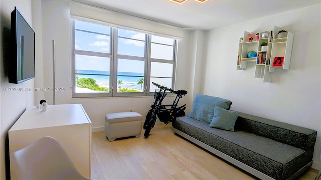living area with a water view, baseboards, and light wood-style flooring